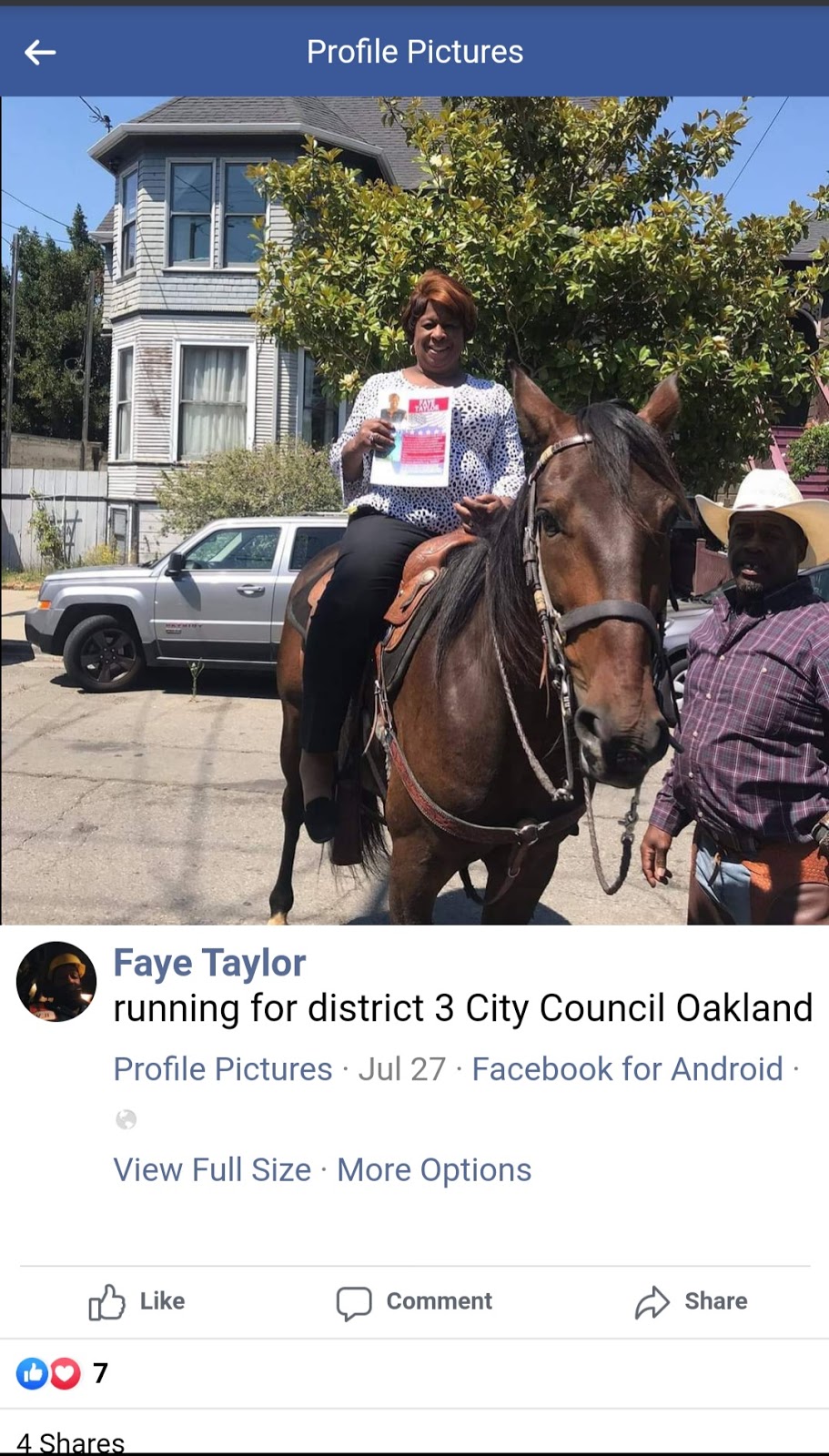 Taylor sits on top of a horse (it is a bay) and holds up a campaign flyer.